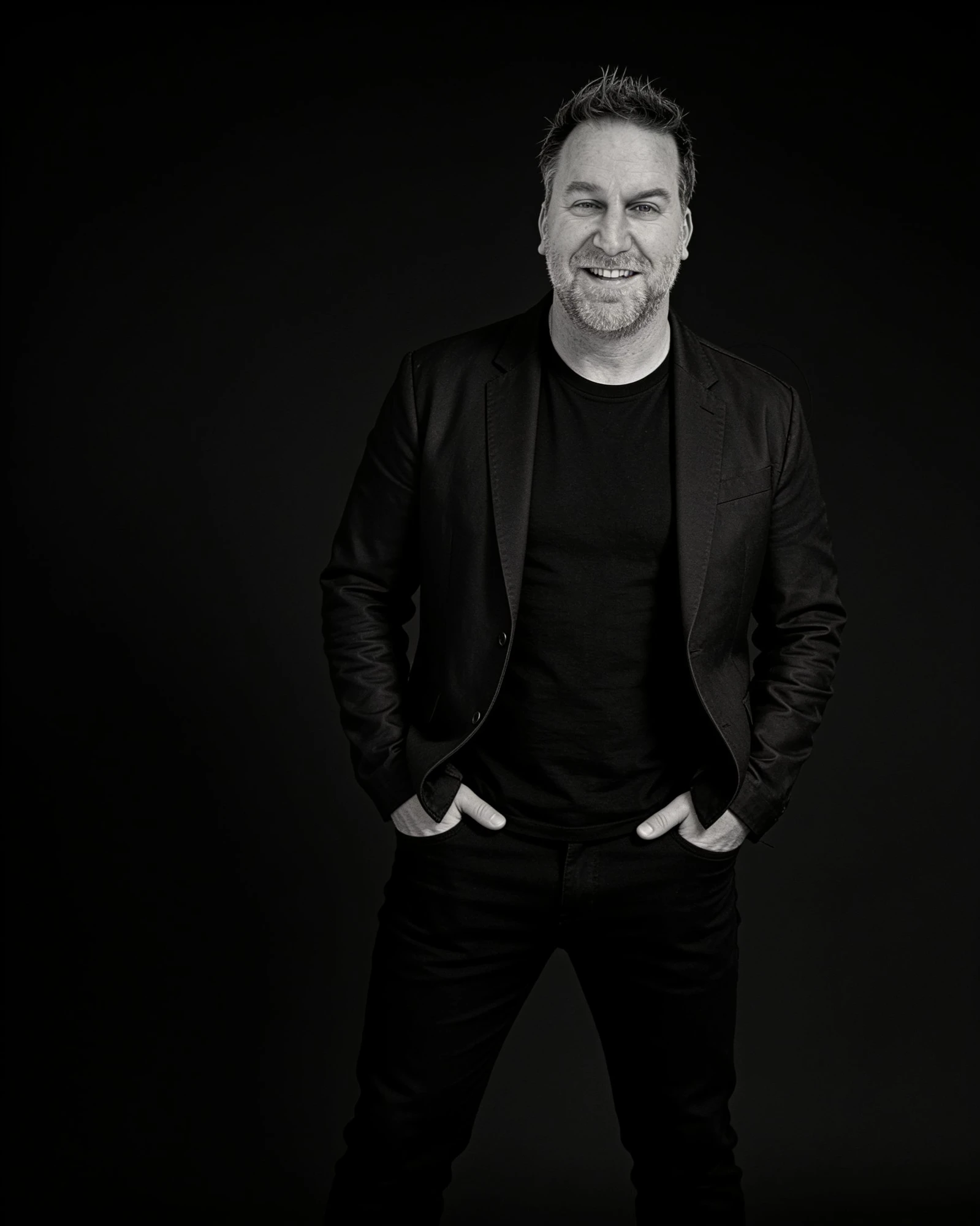 Randy Branam standing with his hands in his pockets against a black studio background