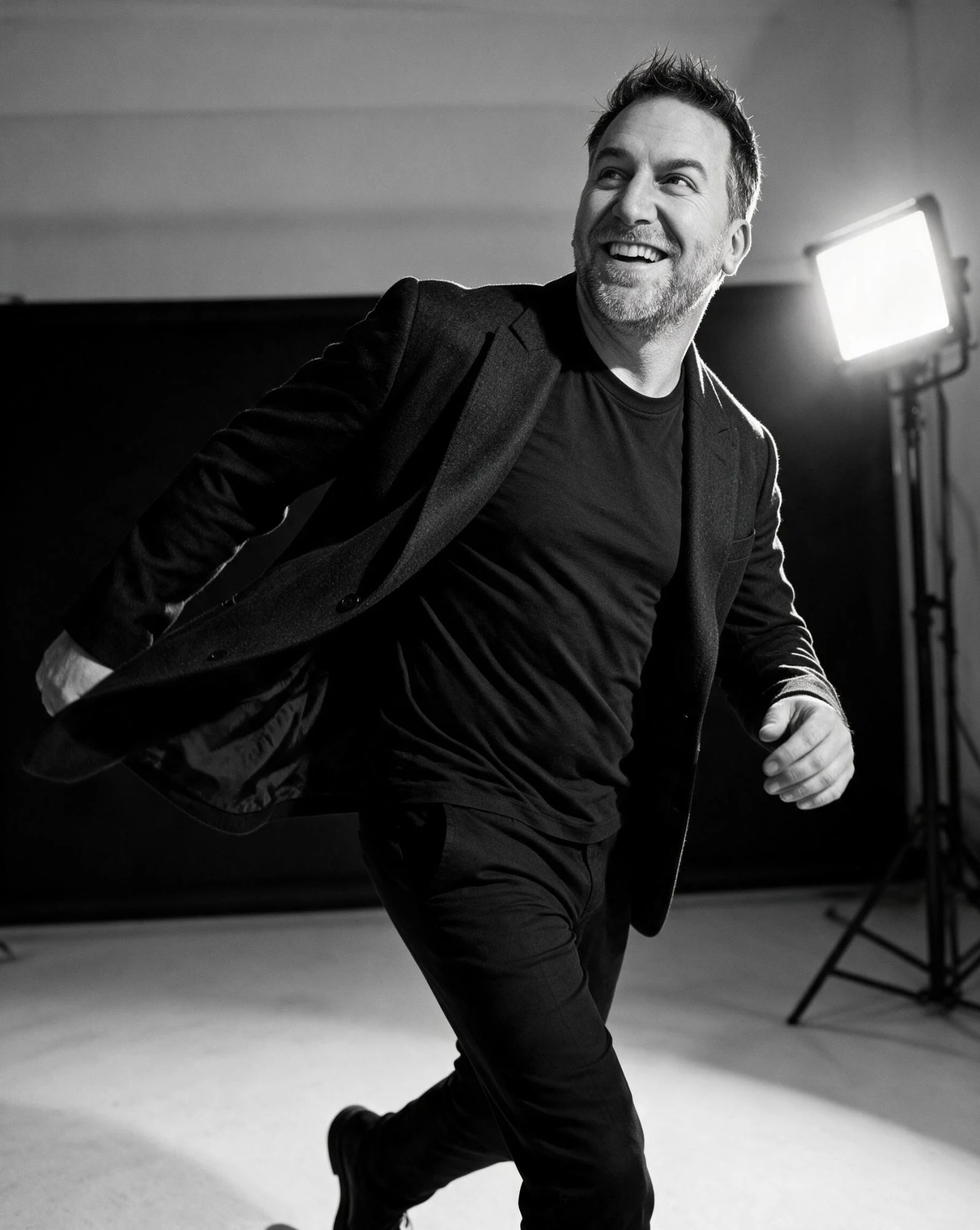 Randy Branam smiling and moving toward the camera in a monochrome studio portrait