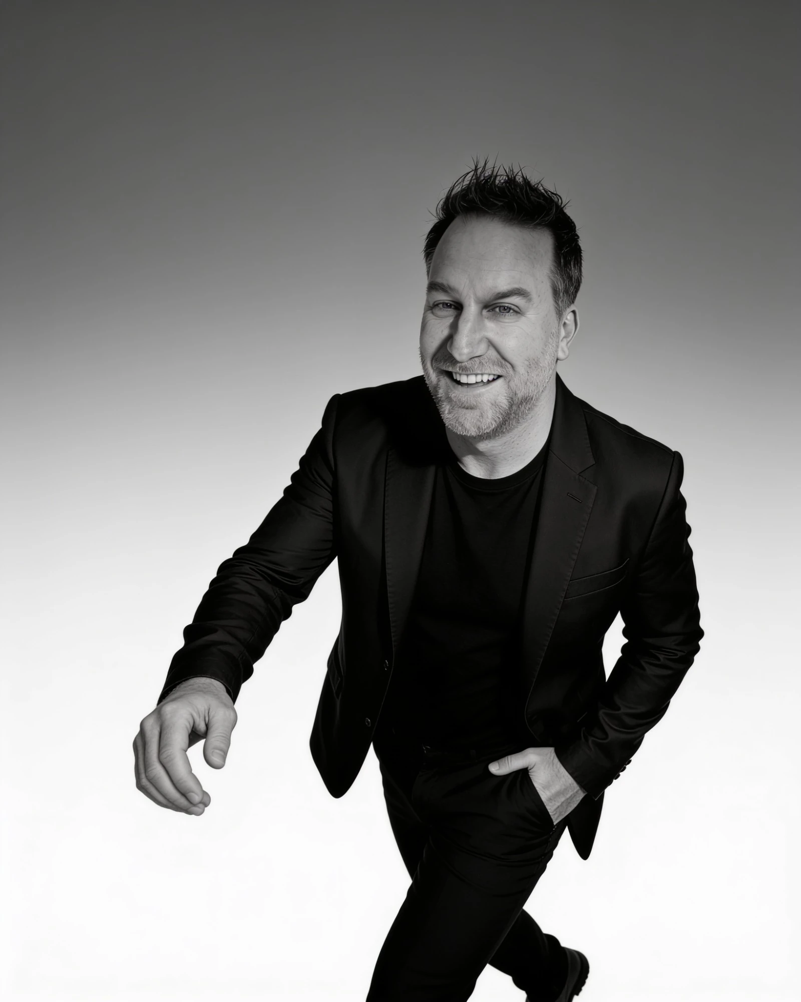 Randy Branam smiling and stepping toward the camera in a monochrome studio portrait
