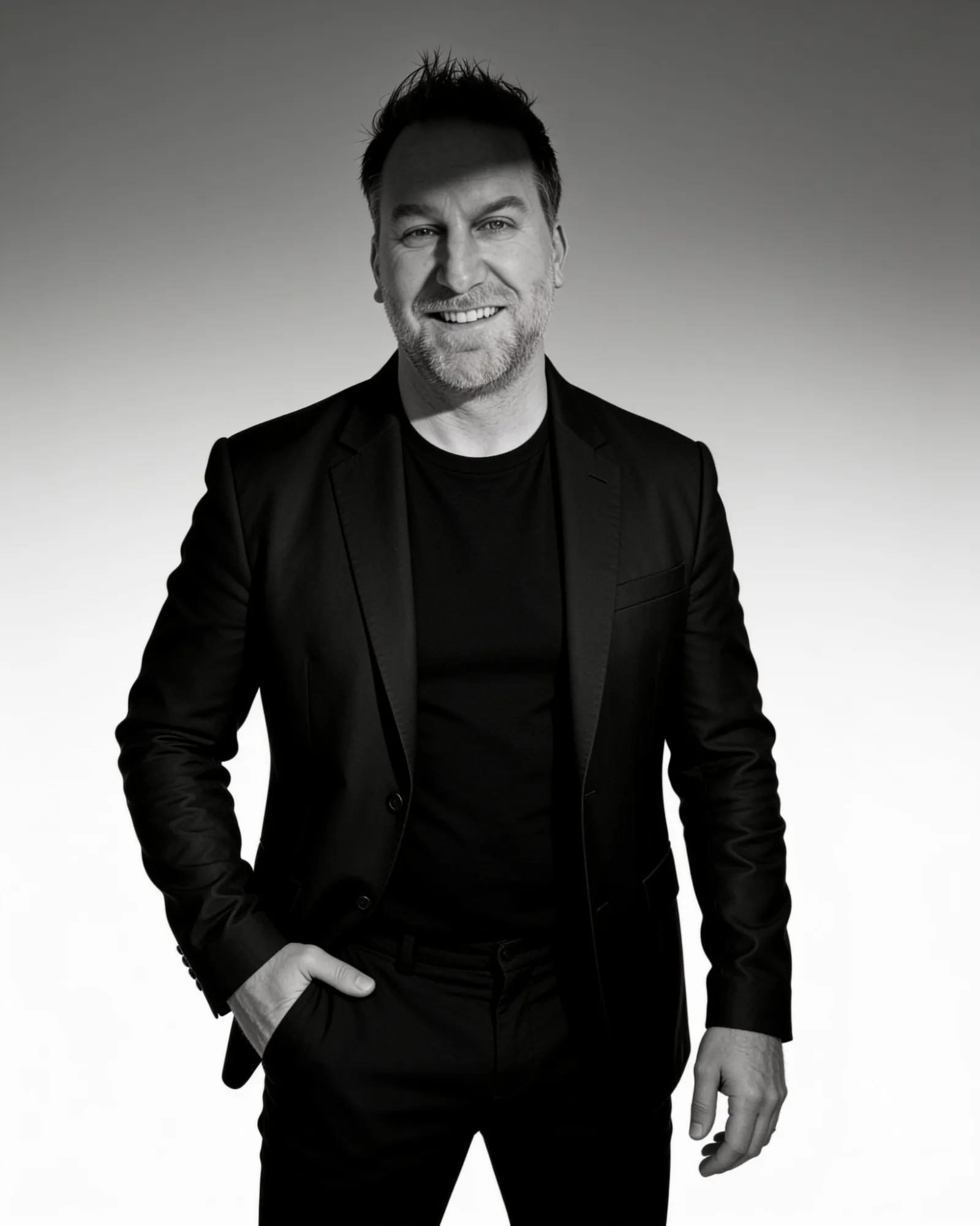Randy Branam standing and smiling in a black-and-white studio portrait
