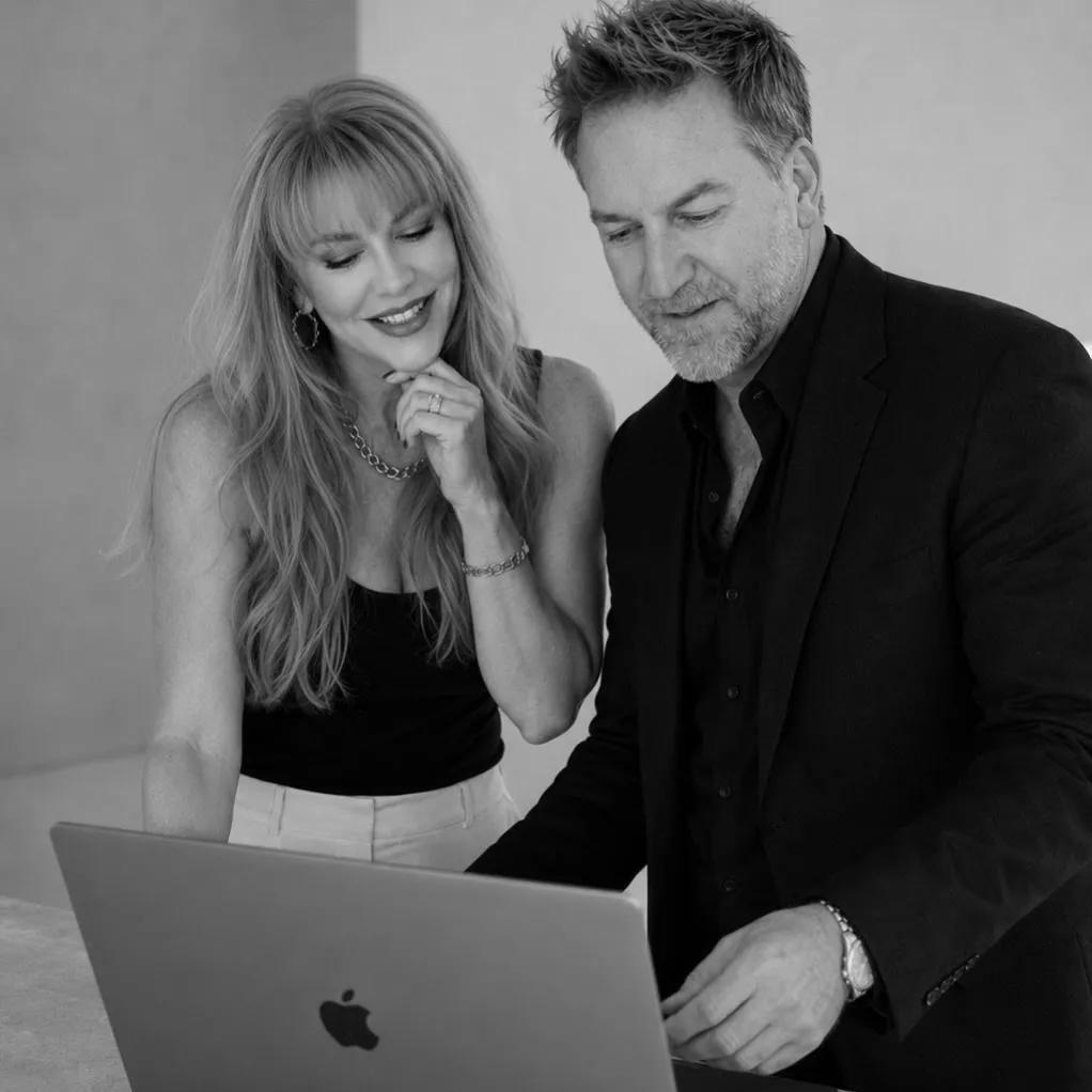 Summer and Randy Branam laughing together in a bright monochrome studio
