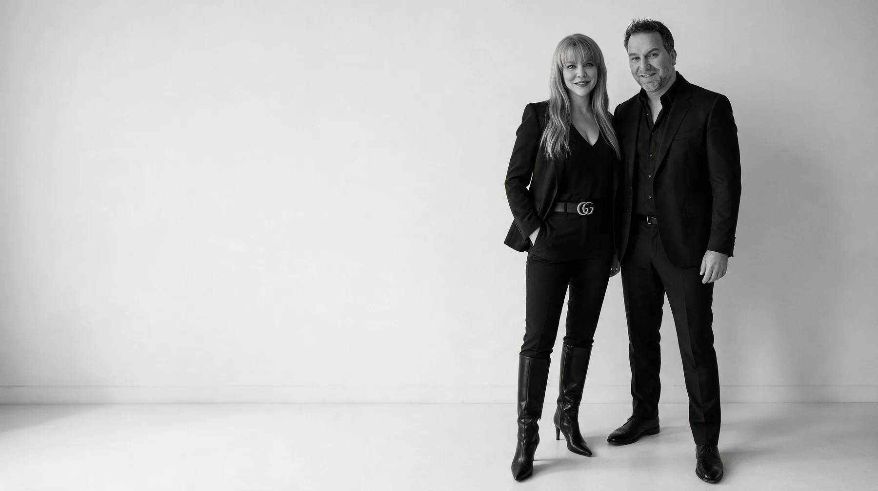 Summer and Randy Branam standing together and smiling in a monochrome studio portrait