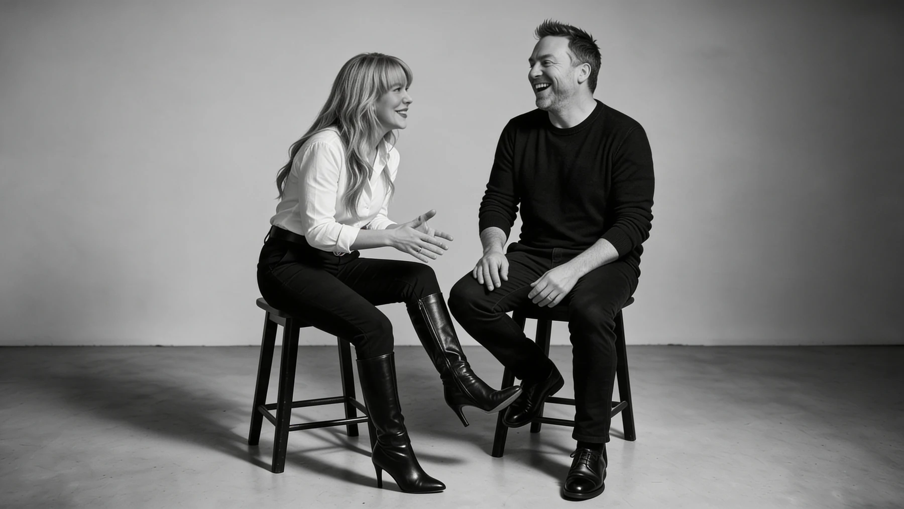 Summer and Randy Branam seated on studio stools, laughing mid conversation in a monochrome portrait