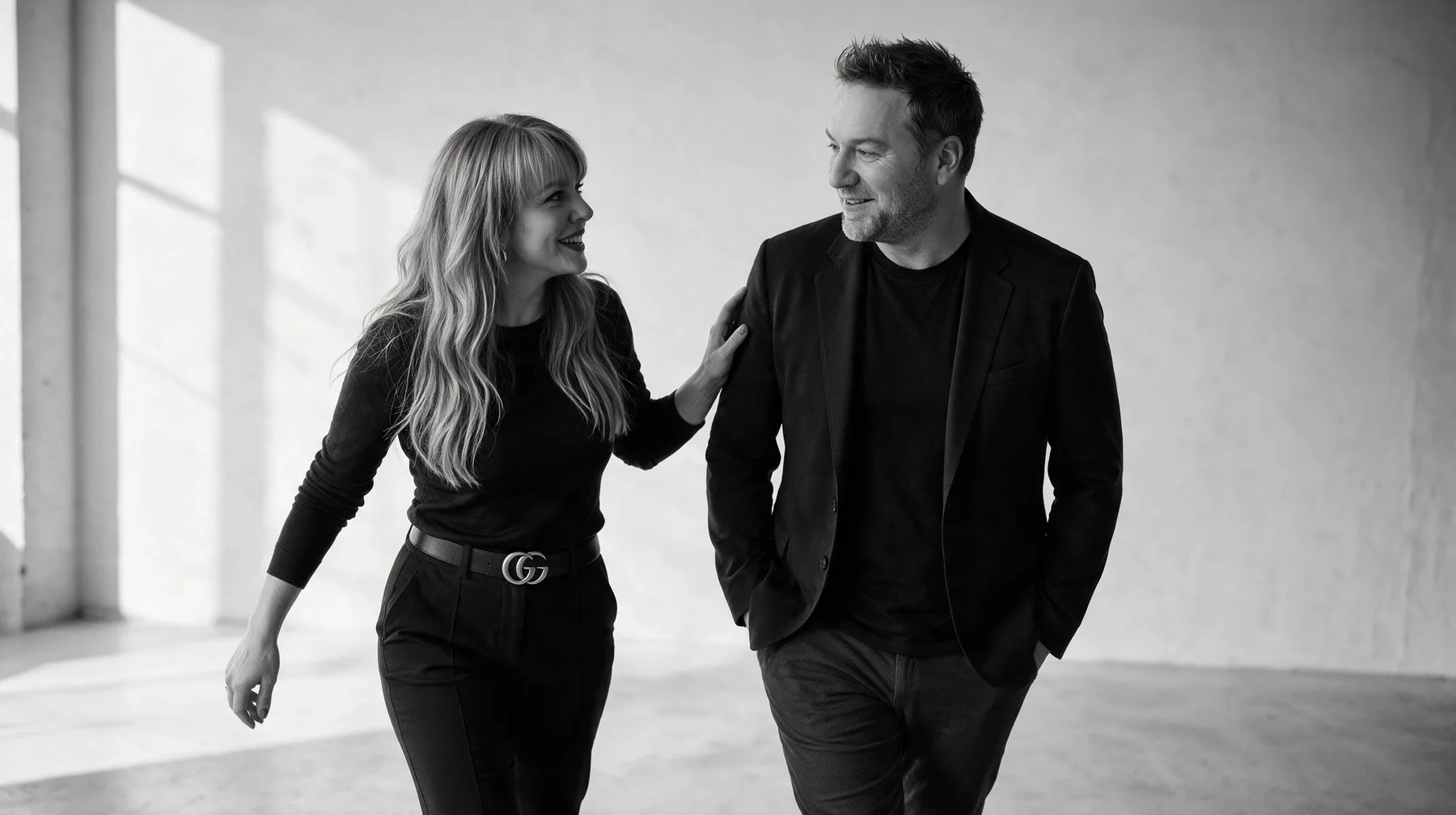 Summer and Randy Branam walking together and smiling in a monochrome studio portrait