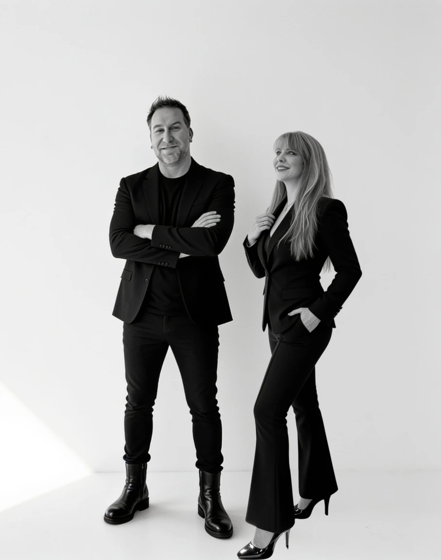 Summer and Randy Branam standing together in tailored black outfits in a monochrome studio portrait